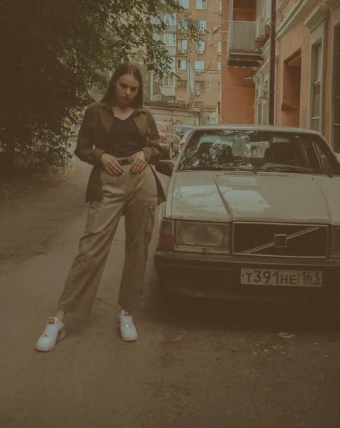 woman in gray jacket standing beside white mercedes benz car