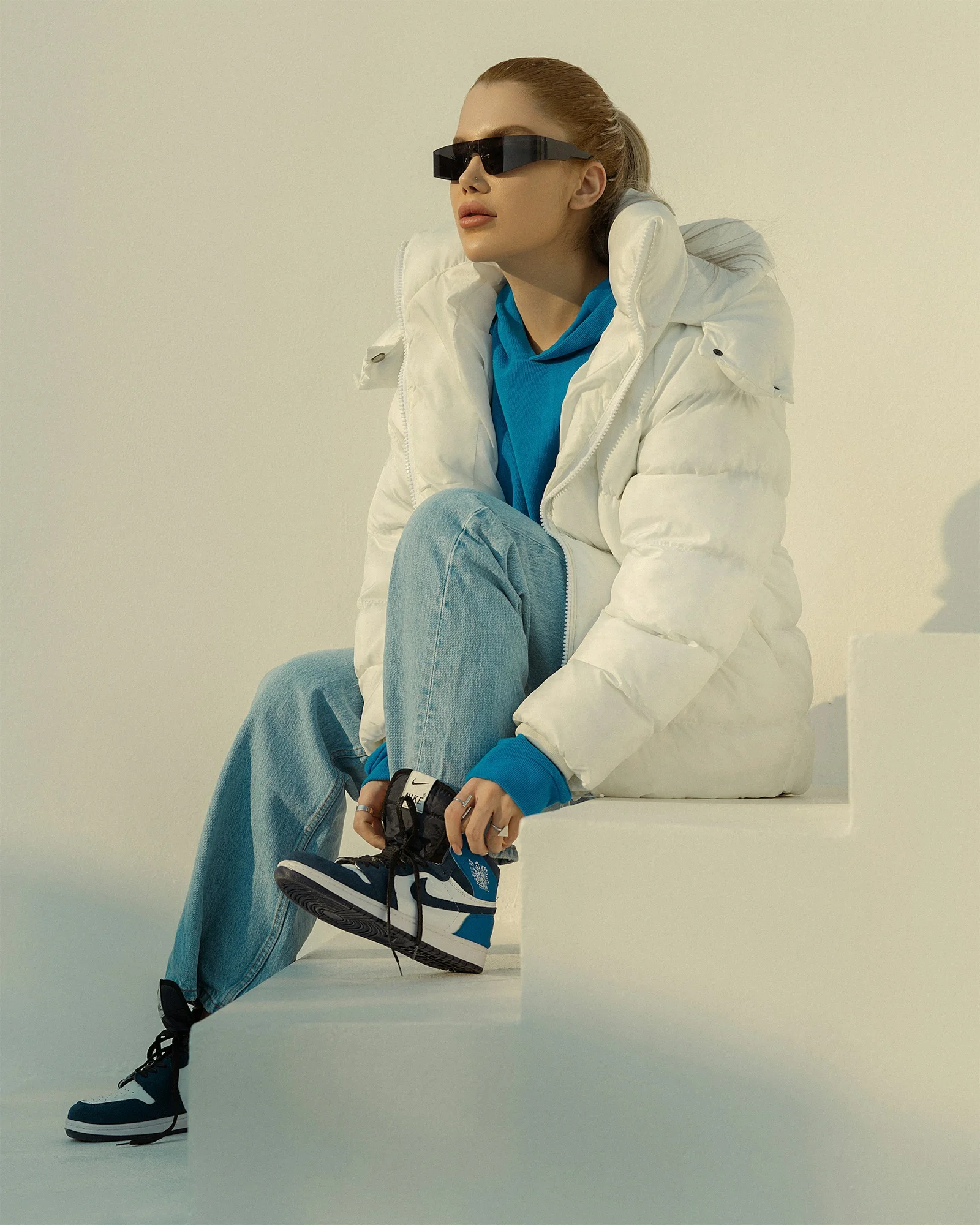 a woman sitting on a ledge wearing sunglasses