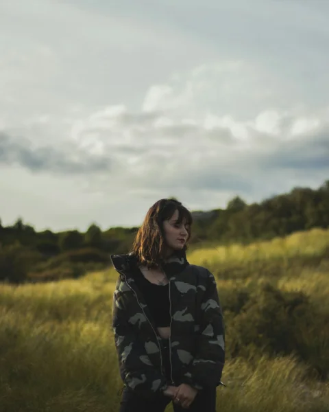woman standing on green field glancing her right side