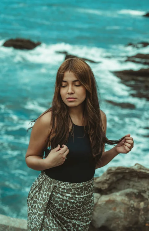 a woman standing on top of a cliff next to the ocean