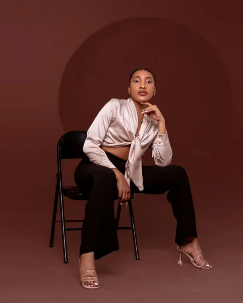 A stylish woman poses confidently on a chair