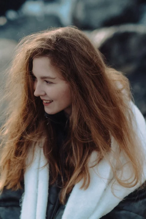 A smiling woman with long, flowing red hair