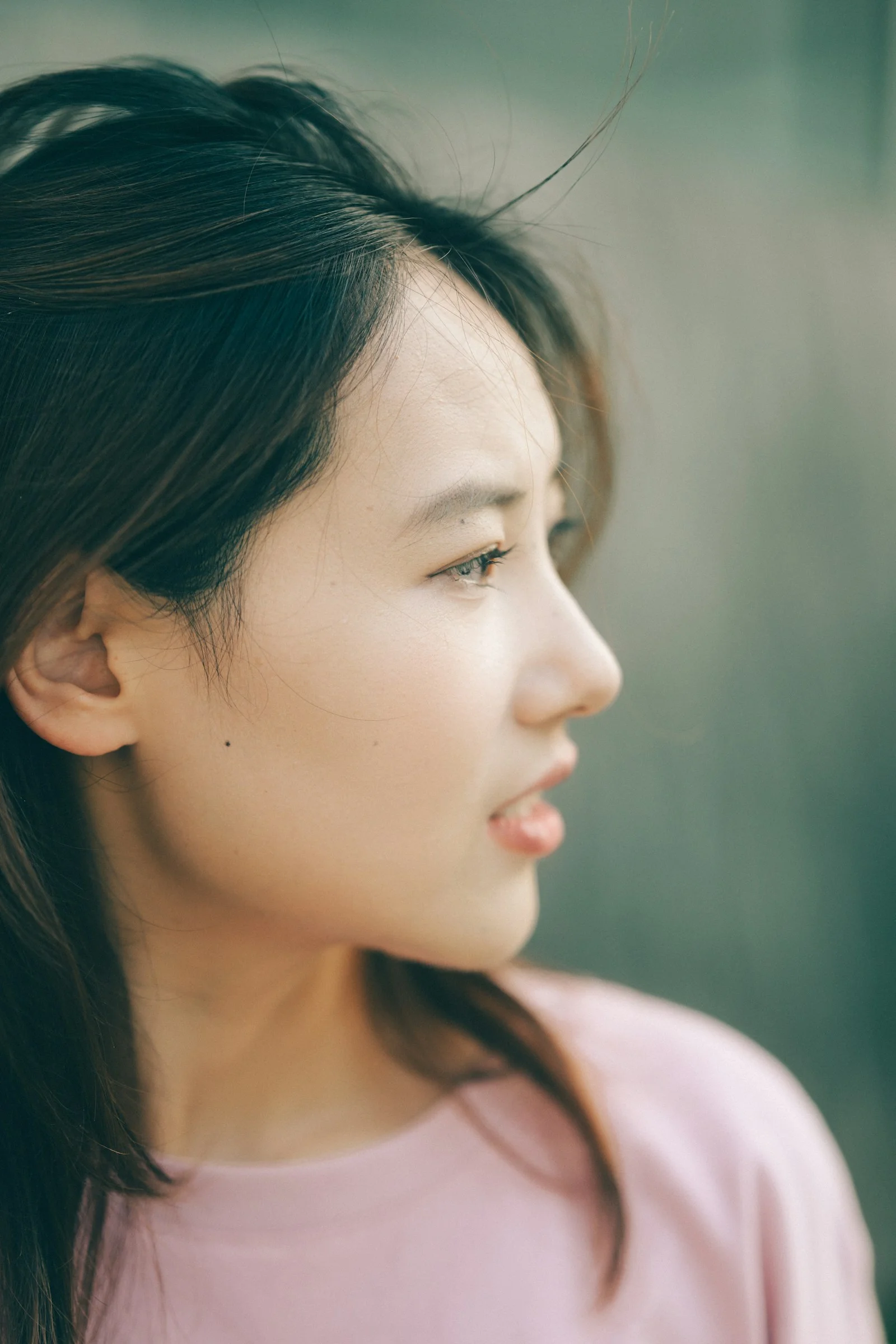 A woman with dark hair in a pink shirt looking away