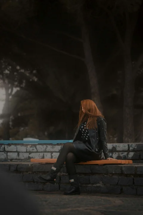 a woman with red hair sitting on a bench