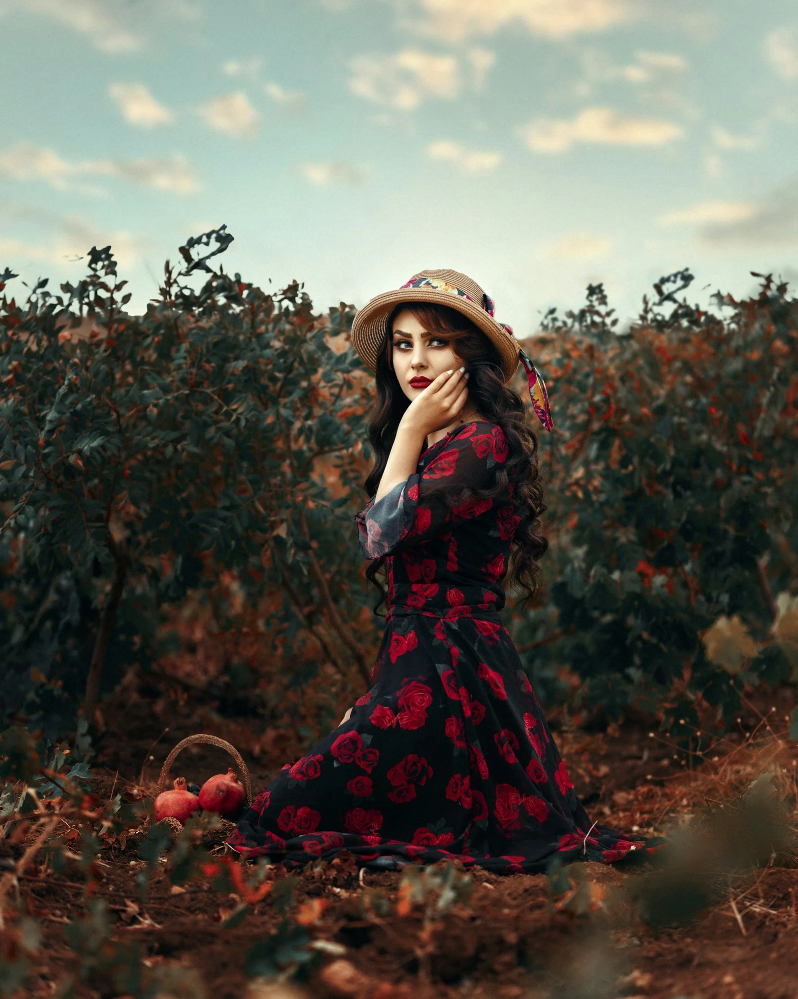 a woman in a red dress and hat sitting in a field