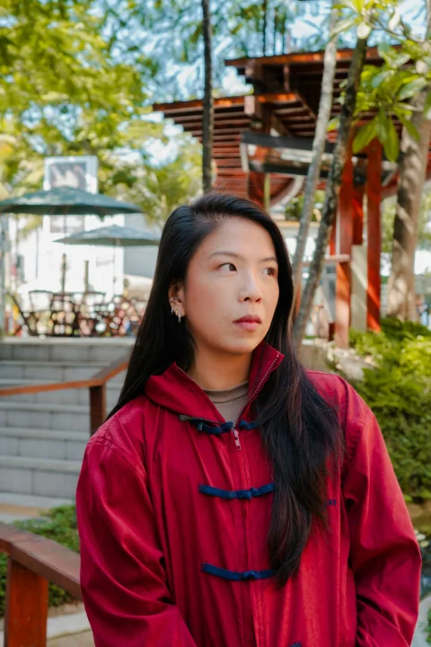 A woman in a red jacket stands outdoors