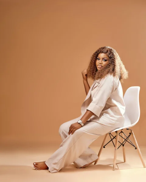 Woman in beige suit sitting on a white chair