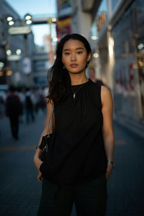 a woman standing on a sidewalk in a city