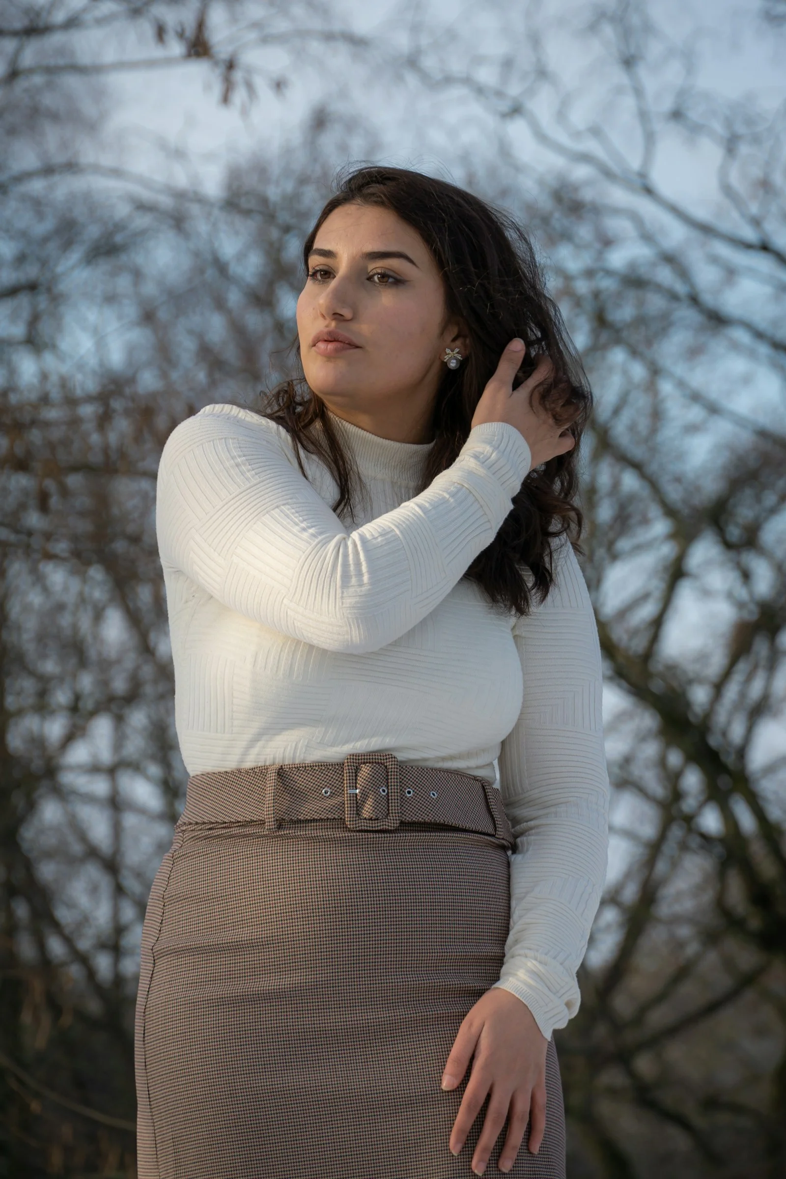 a woman in a white sweater and brown skirt