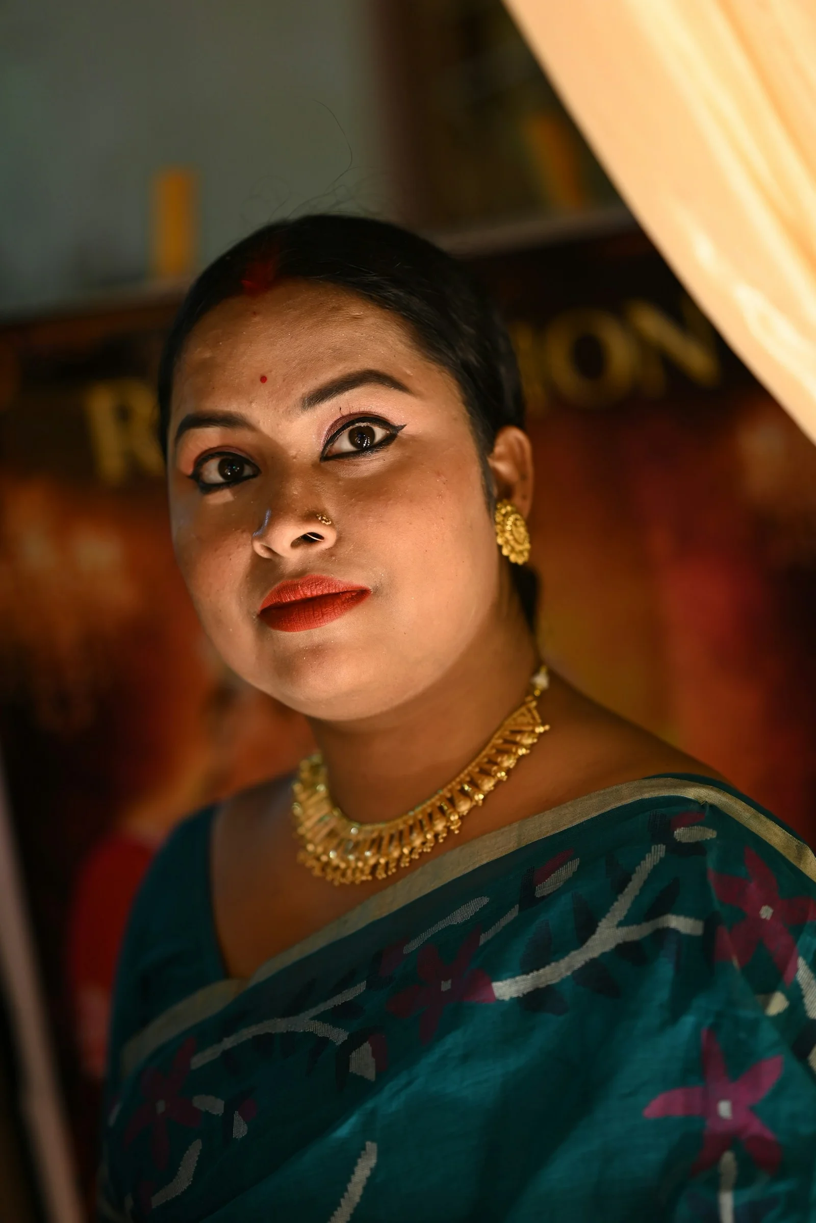 A woman in a teal sari with gold accessories