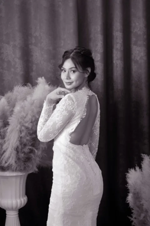 a woman in a white dress standing next to a vase