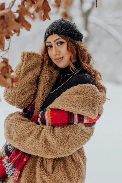 一位女子站在雪中，双臂环抱头部