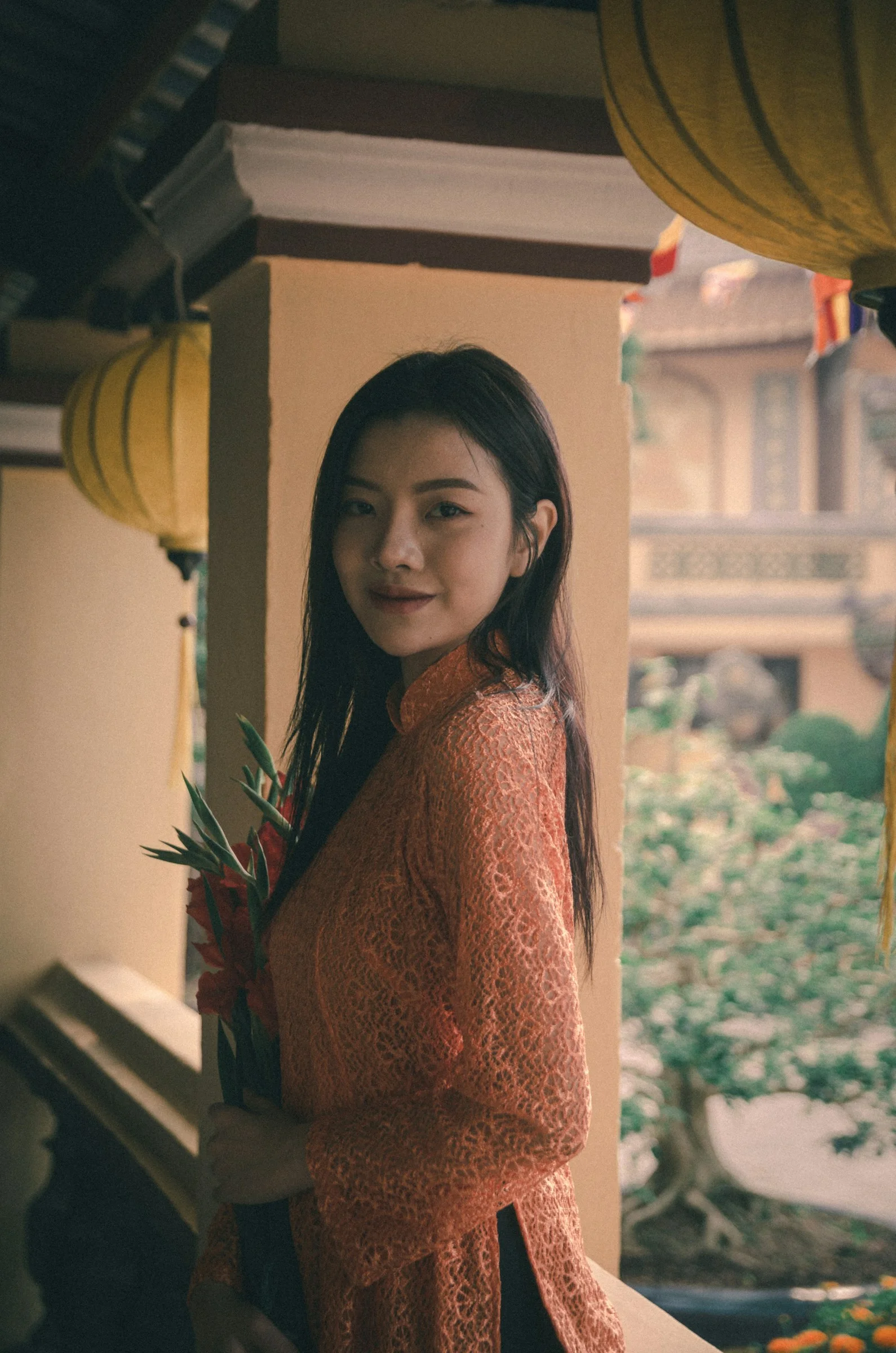 a woman standing on a porch holding a bouquet of flowers