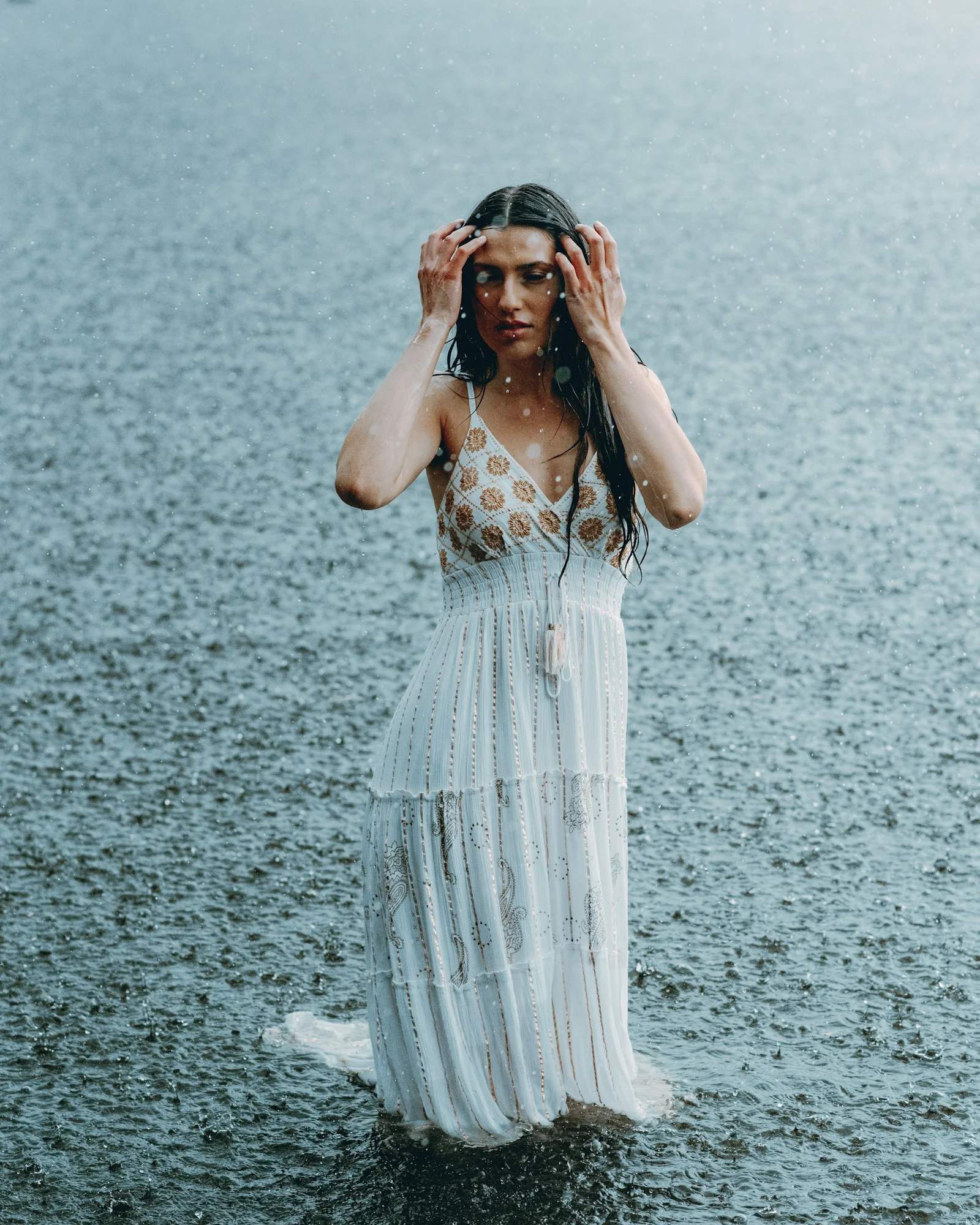 Woman stands in the rain, holding her hair