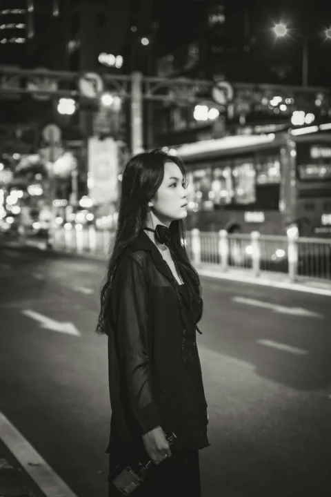 a woman standing on the side of a road at night
