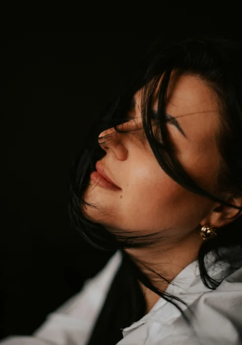 a woman in a white shirt and gold earrings