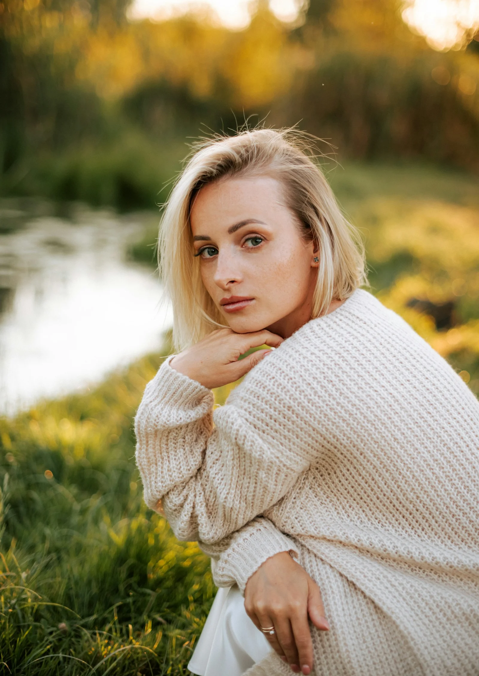 Young woman with blonde hair in a cream sweater outdoors