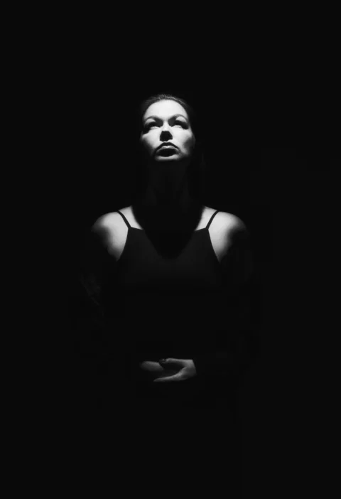 a woman standing in the dark with her arms crossed