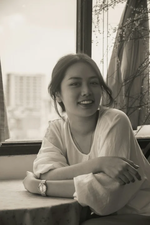 穿白衬衫的微笑女人坐在窗边的桌旁