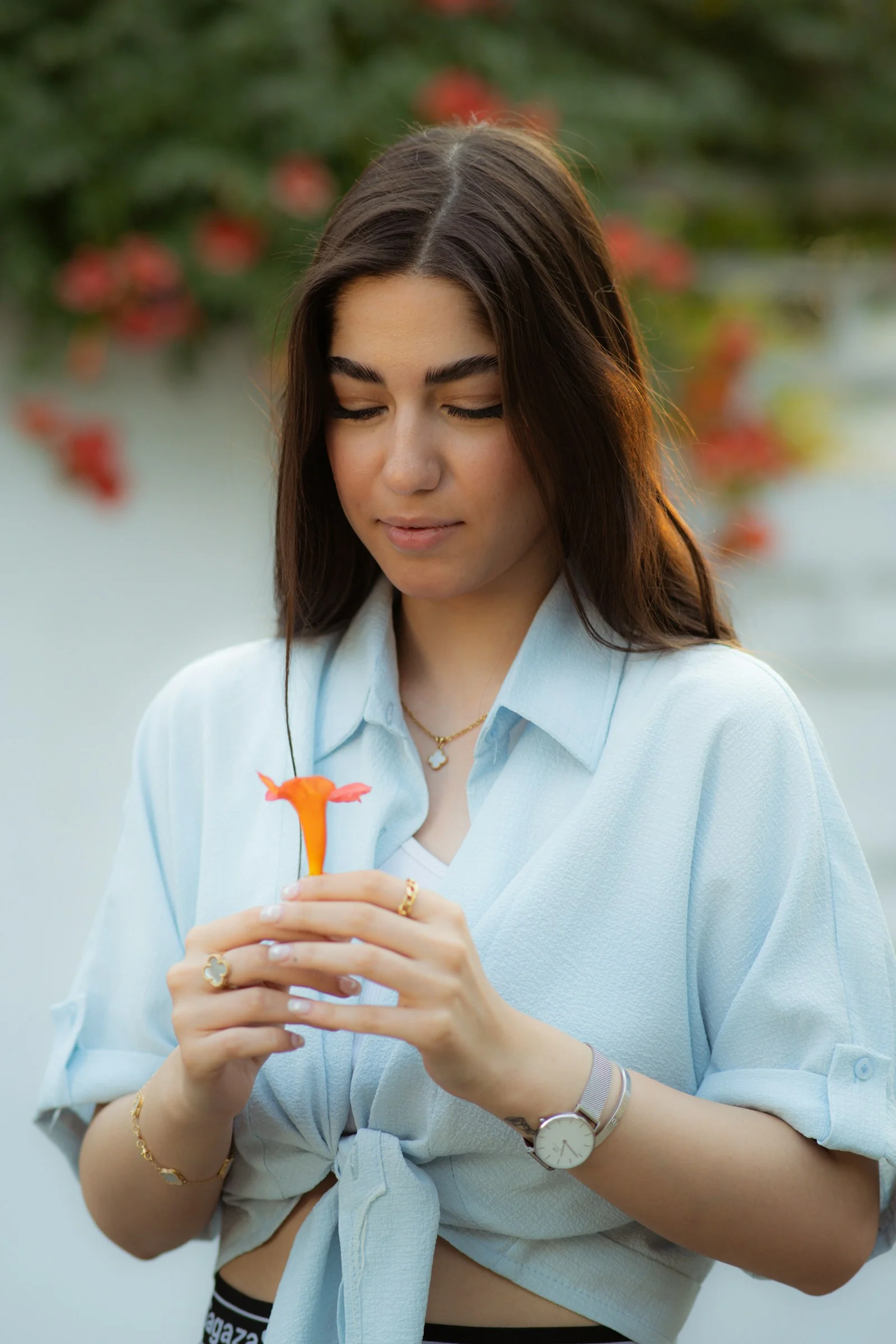 A woman is admiring a flower thoughtfully