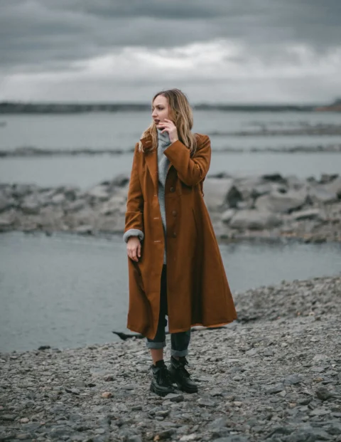a person in a long coat on a rocky beach