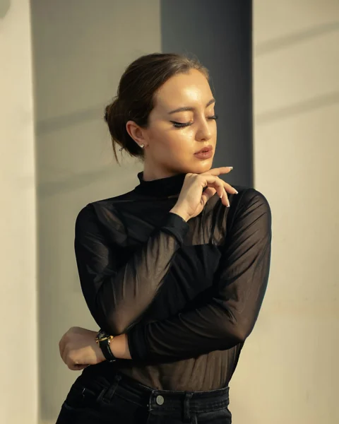 A woman in black shirt and jeans leaning against a wall