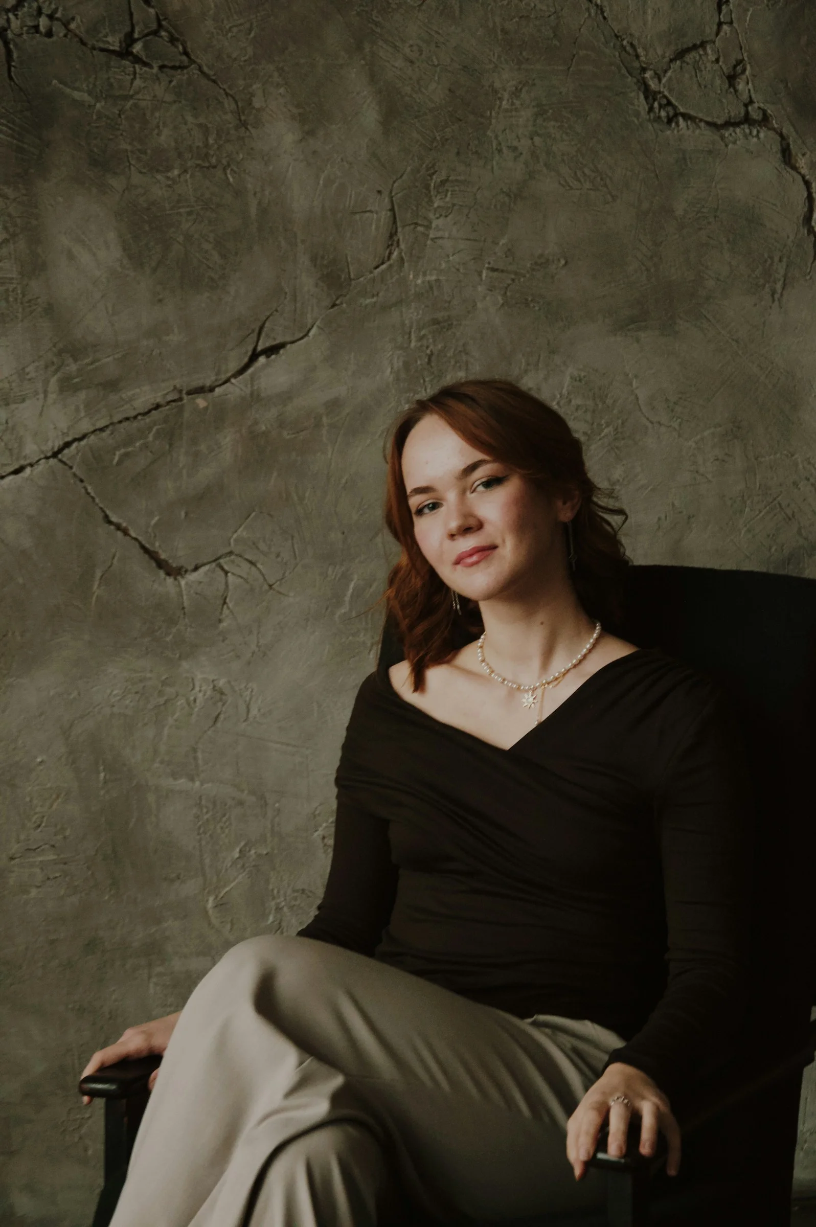 Woman sitting in a chair against textured wall