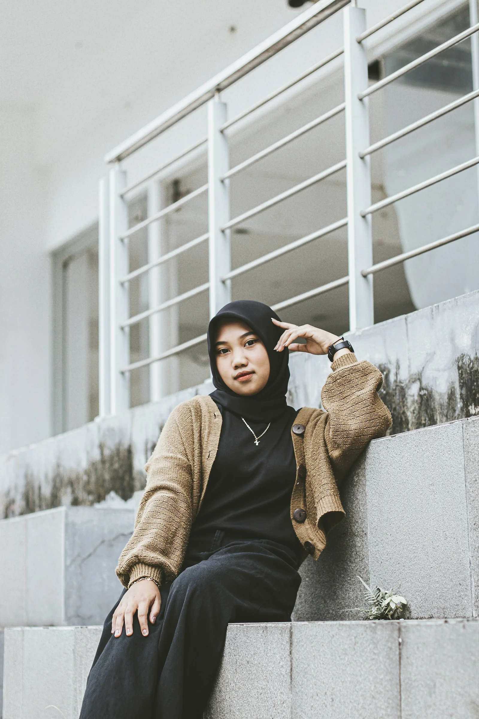 戴著希賈布頭巾坐在矮牆上的女子