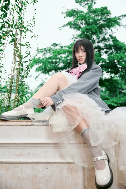 Young woman in grey blazer and white skirt adjusting sock