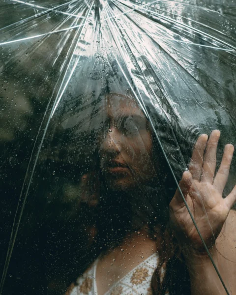 A woman touches the rain through an umbrella