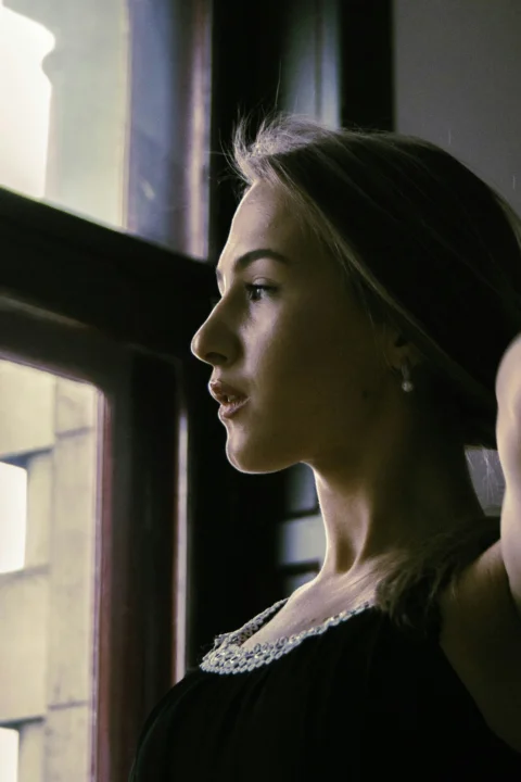 a woman in a black dress looking out a window