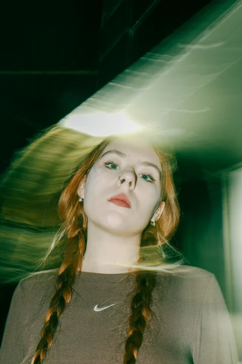 A woman with long red hair wearing a brown shirt