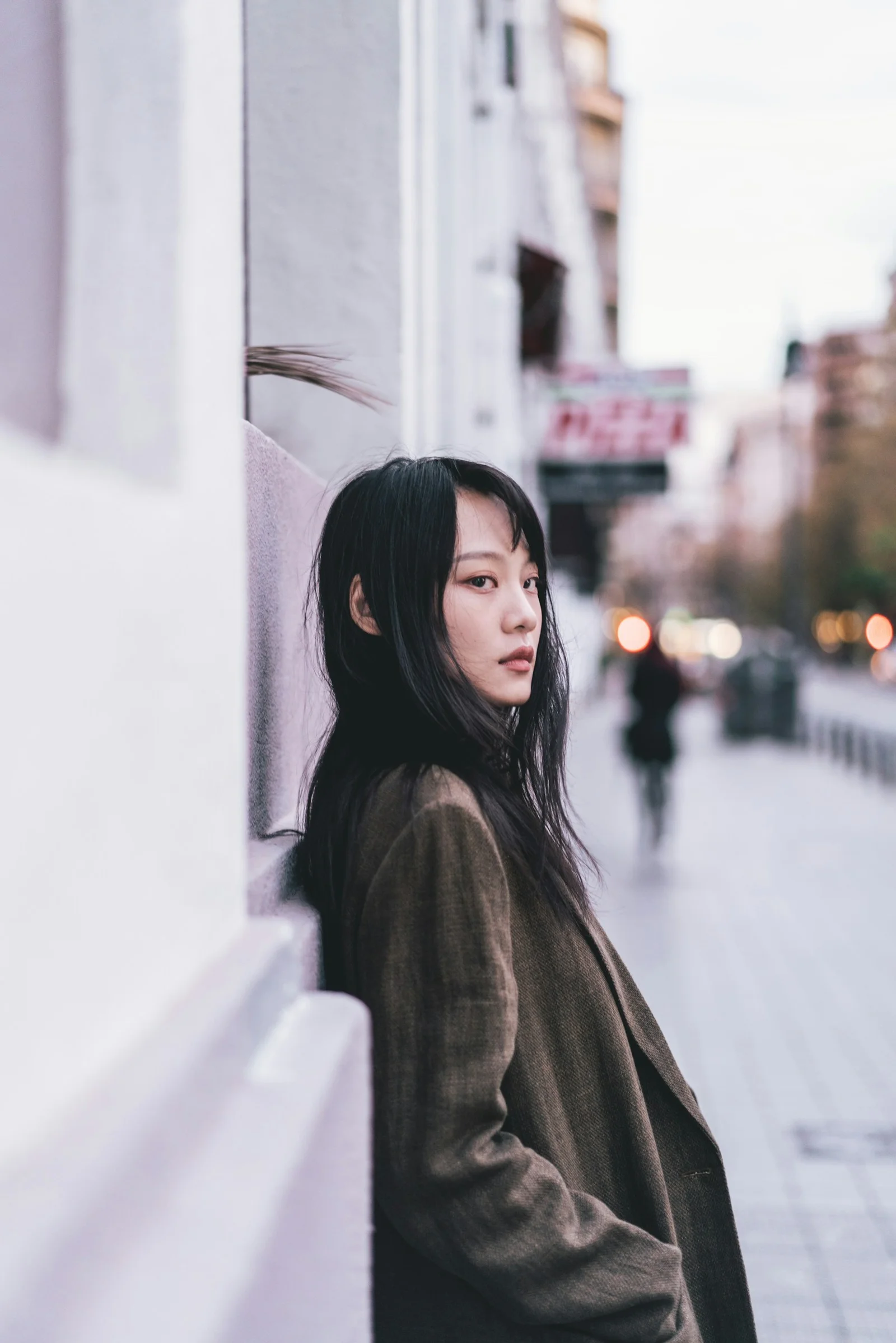 女子靠在路旁的建筑物上