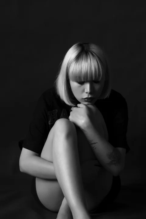 a black and white photo of a woman sitting on the ground