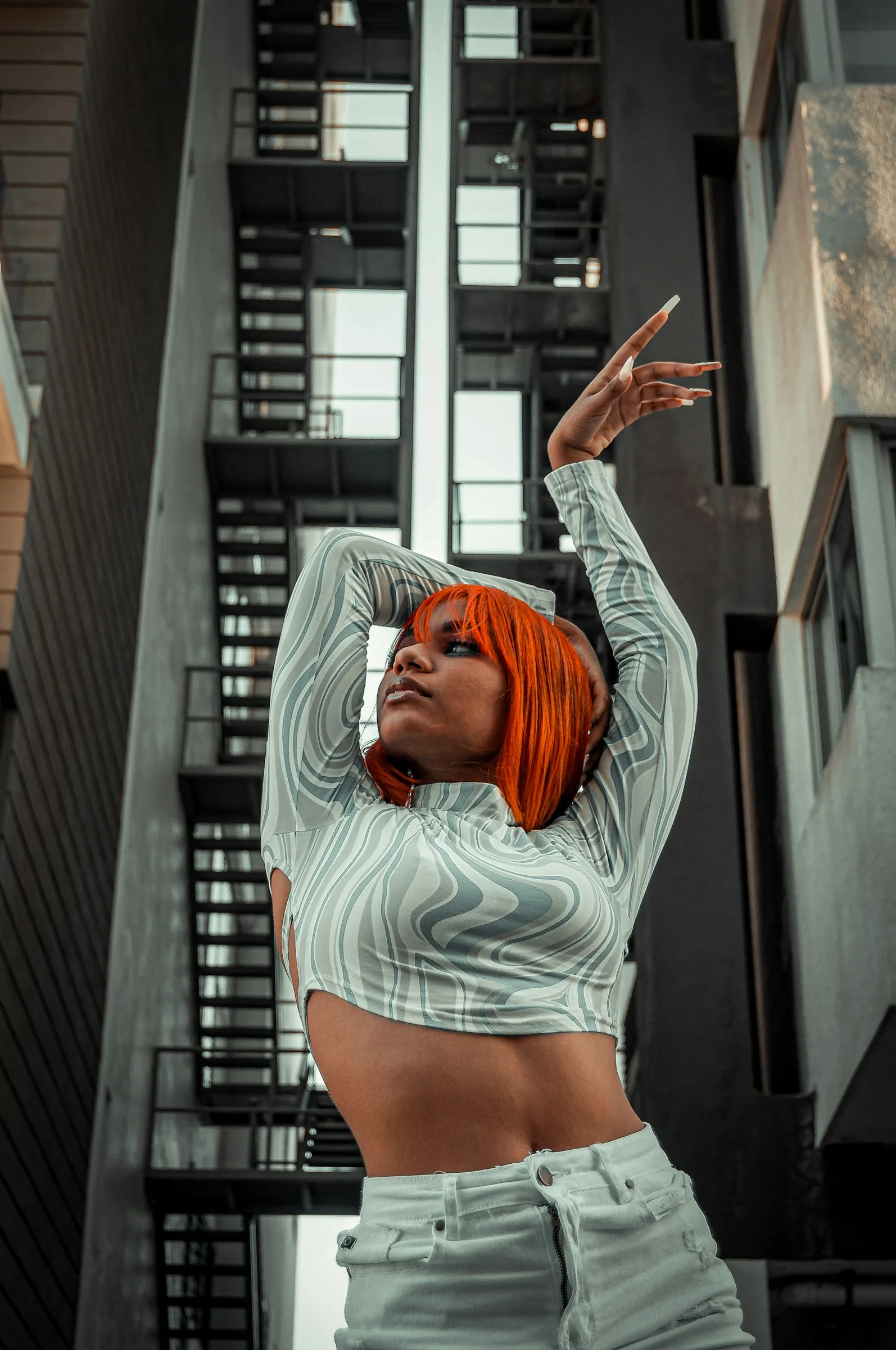 a woman with orange hair is posing in front of a building