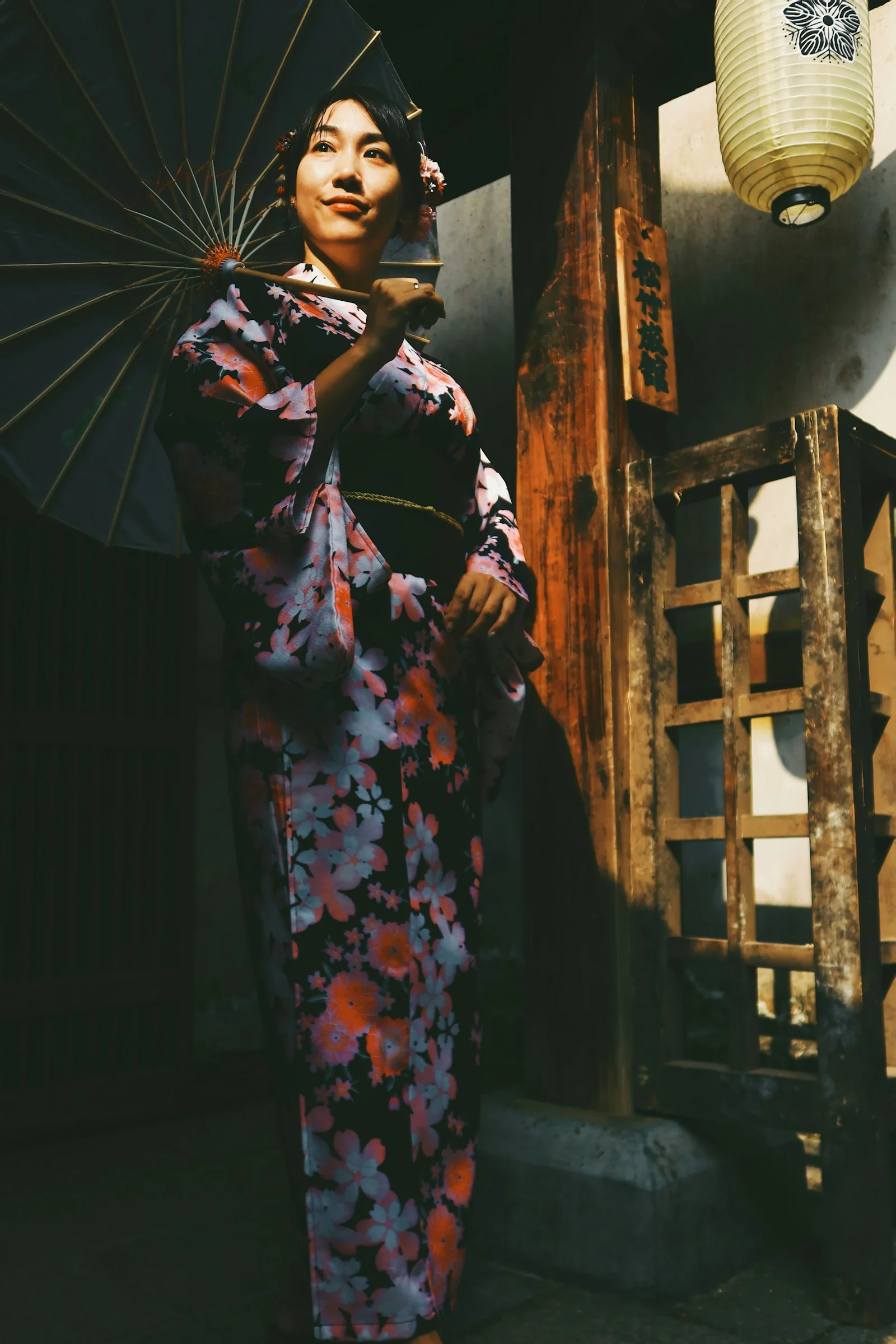 穿著黑紅色花卉和服的女子站在棕色木樓梯上