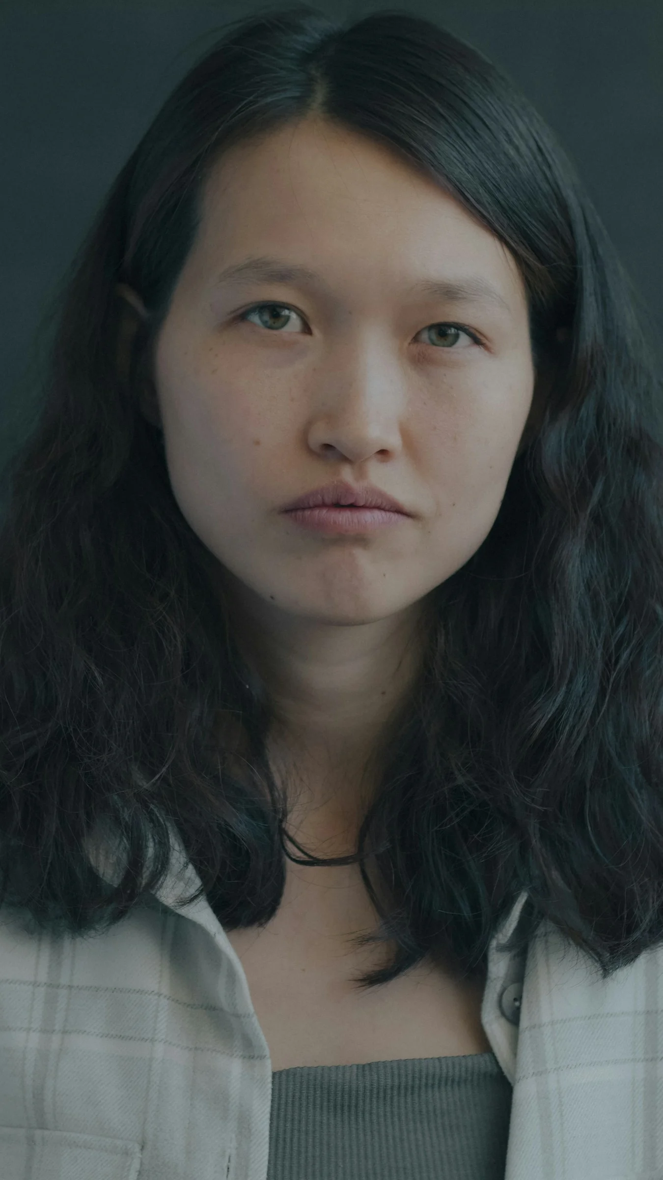 一位留着深色长卷发、身穿浅色格子衬衫的女人
