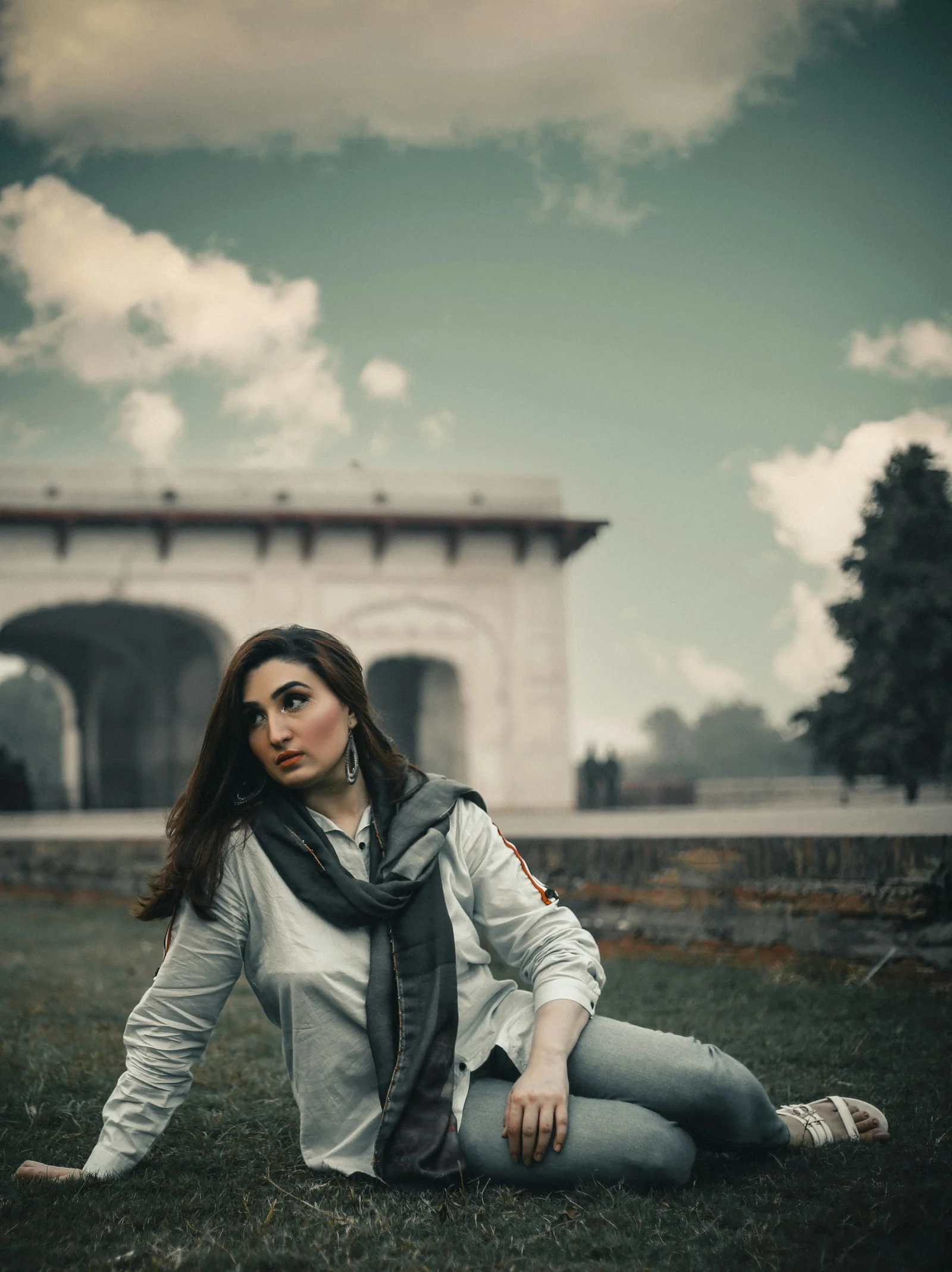 Woman poses on grass near a historical building