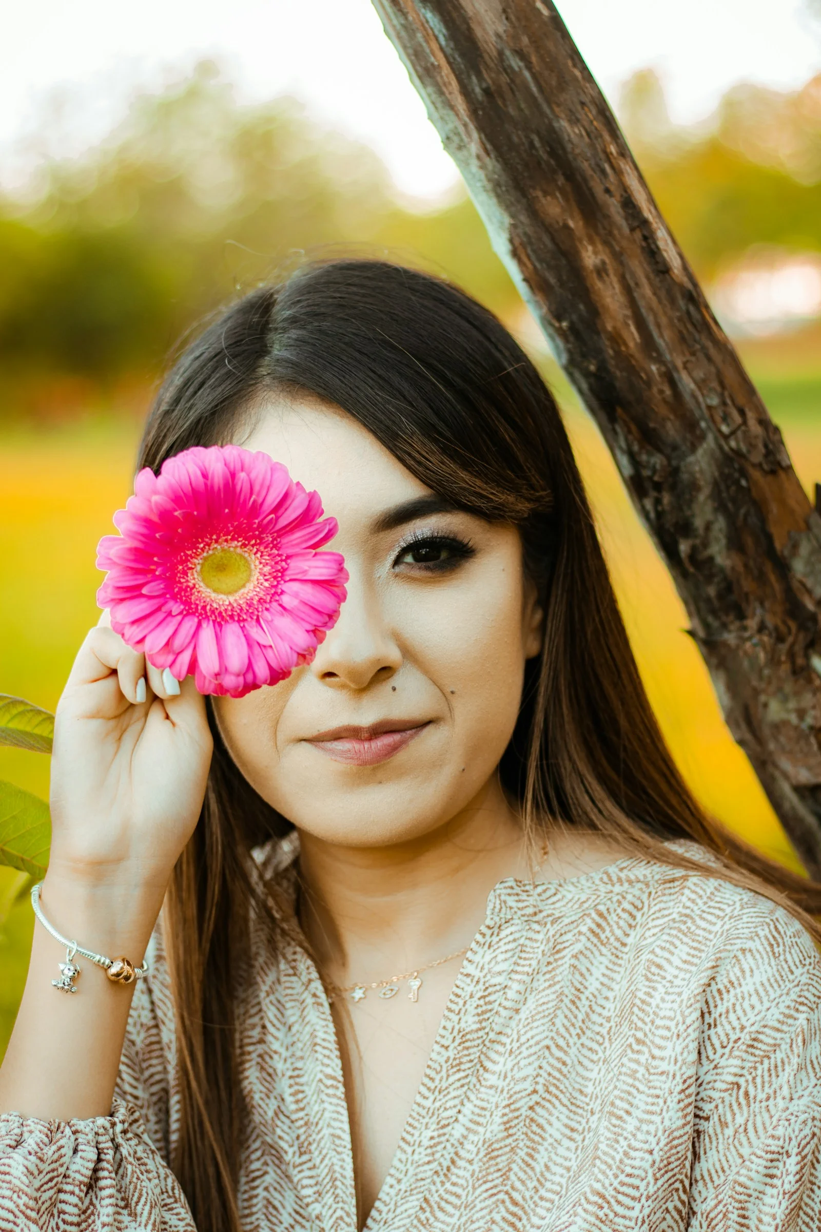 a woman holding a pink flower in front of her face