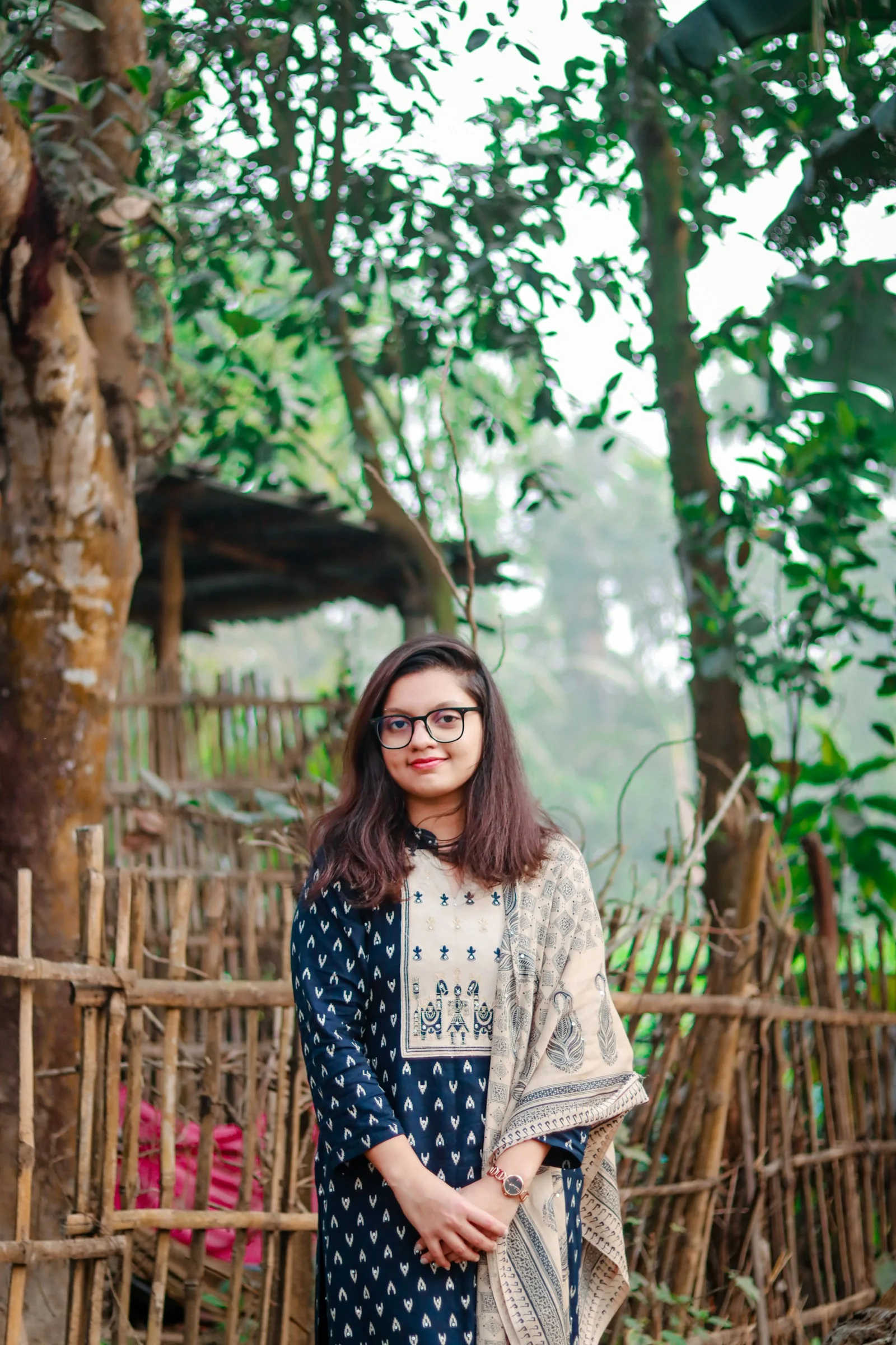 Young woman standing outdoors near a wooden fence