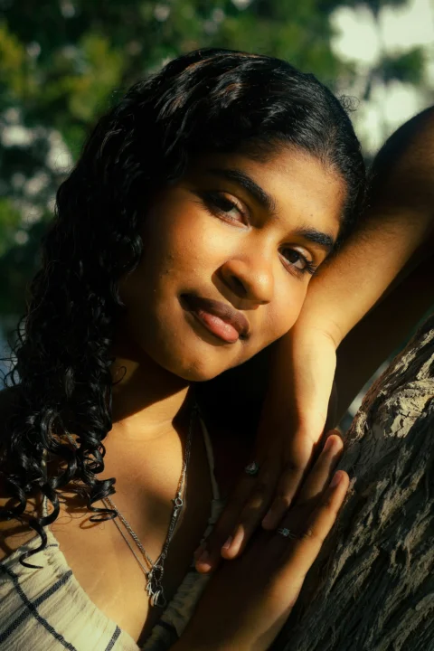Young woman leaning on a tree trunk
