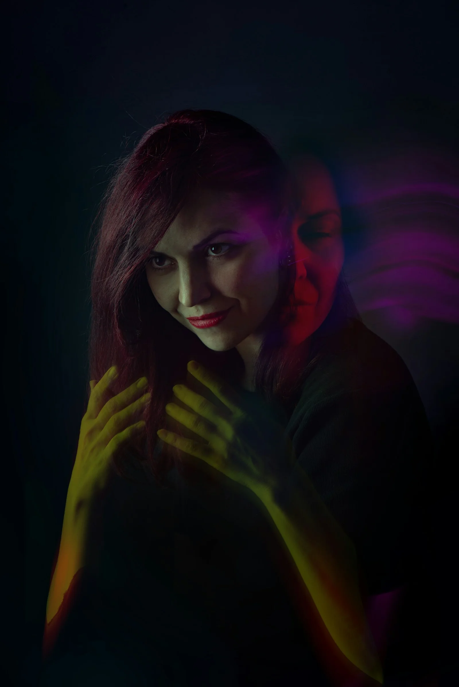 A woman standing in the dark with her hands on her chest