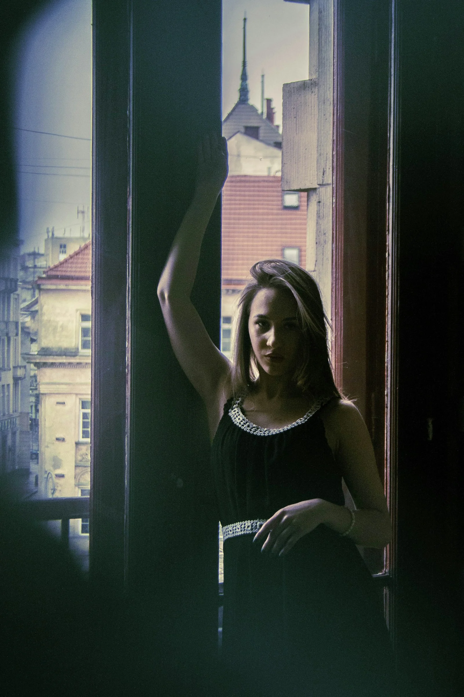 a woman in a black dress looking out a window