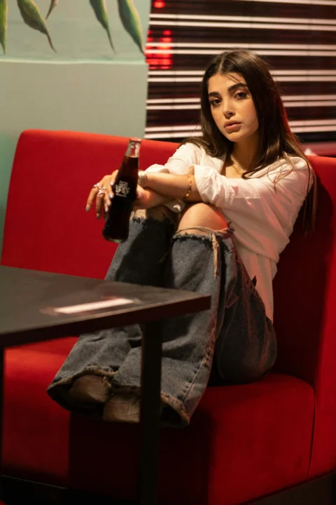 A woman sits in a booth holding a soda