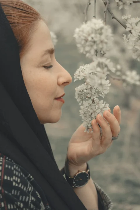 woman in black hijab holding white flower