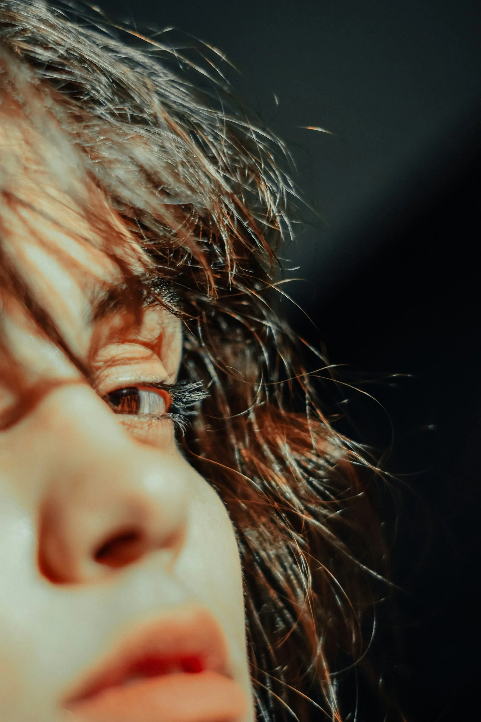 A close up of a woman's face with hair blowing in the wind