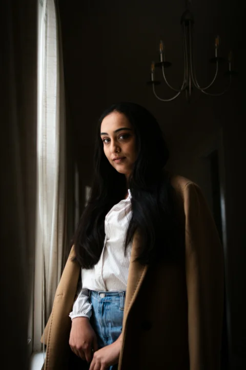 a woman standing next to a window in a room