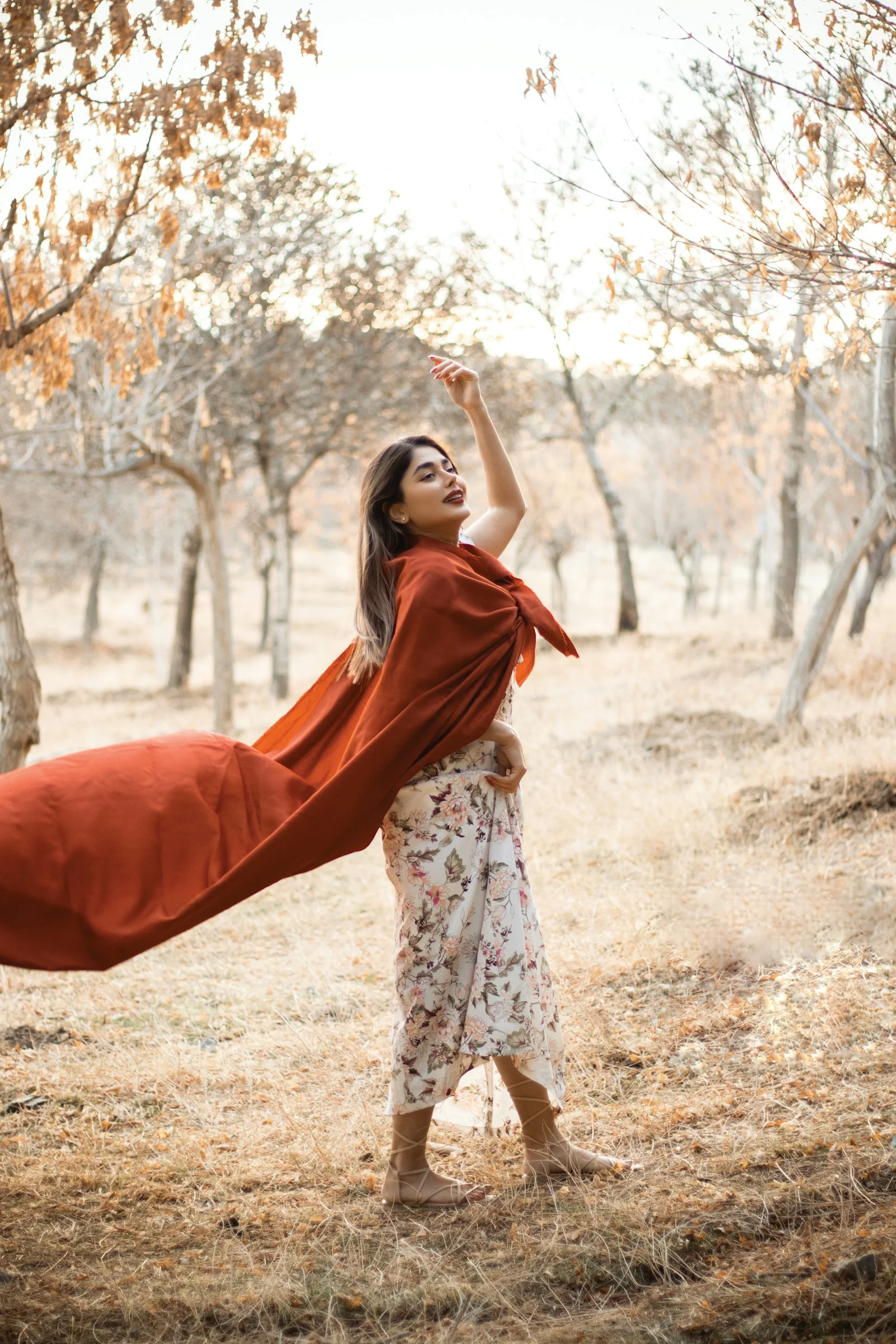 a woman standing in a field holding a red blanket