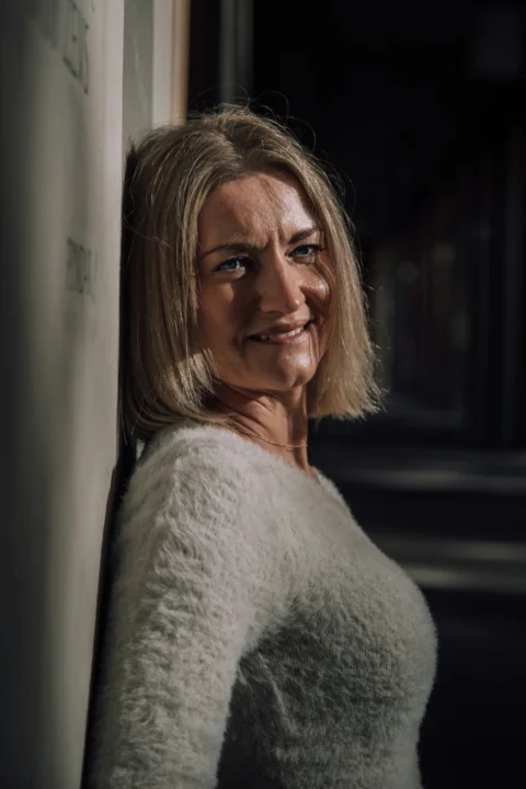 A woman leaning against a wall with a smile on her face