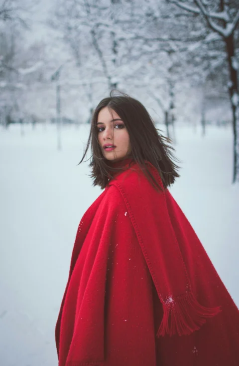 a woman in a red coat standing in the snow